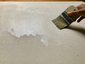 a stretched cotton duck canvas is being washed with luke warm water, since cold water tends to bead up more.